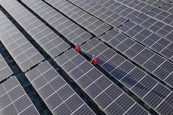 Trabajadores inspeccionando paneles solares en el tejado de una planta de energía en Fuzhou, en la provincia de Fujian, en el sur de China.