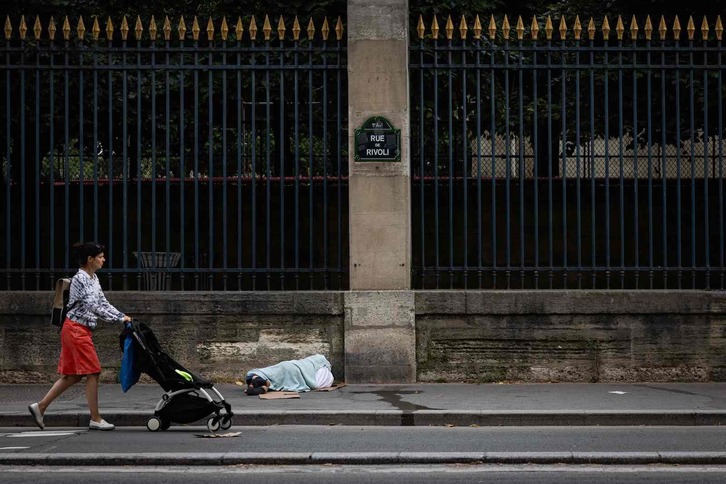 Una mujer pasa ante una persona sin hogar, en París. 
