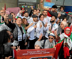 Atletas de la delegación palestina posan con aficionados a su llegada a París.