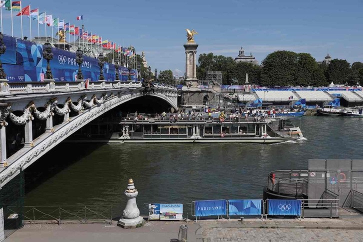 Un barco turístico navega en el Sena, a la altura del puente Alejandro III, después de suspender los entrenamientos del lunes