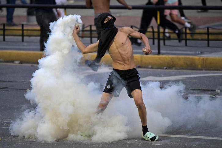 Un opositor devuelve a las fuerzas policiales un bote de humo en las calles de Caracas.