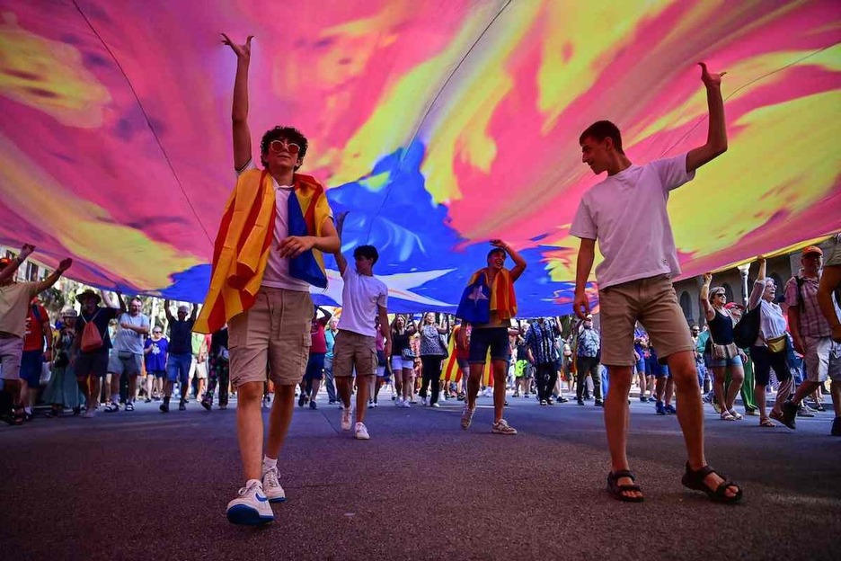 Jóvenes bajo una gran bandera independentista.