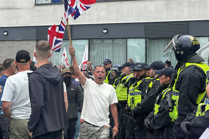 Ultras ingleses exhiben la Unión Jack en presencia de la Policía tras haber asaltado un centro de alojamiento de inmigrantes en Rotherham.