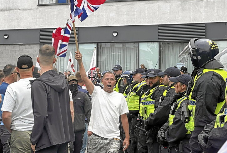 Ultras ingleses exhiben la Unión Jack en presencia de la Policía tras haber asaltado un centro de alojamiento de inmigrantes en Rotherham.