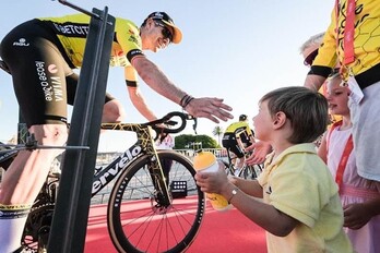 El ganador de la edición pasada, Sepp Kuss, saluda a un niño durante la presentación de la Vuelta en Lisboa.