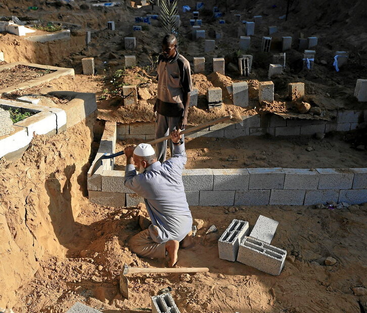 Saadi Hassan Barakeh cava en la arena una tumba en el cementerio de Deir al-Balah.