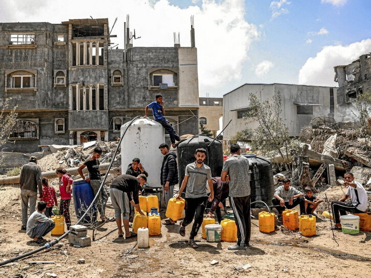 Palestinos se reúnen para llenar sus bidones con agua de las cisternas en Jan Yunis.