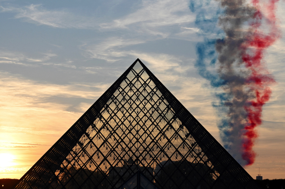 La estela de humo con los colores de la bandera francesa sobre la Pirámide del Louvre diseñada