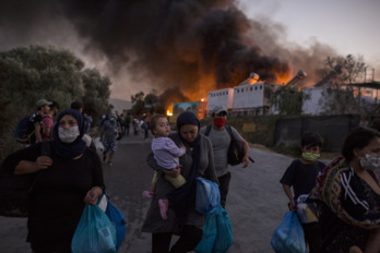 Personas refugiadas huyen del fuego en el campo de Moria.