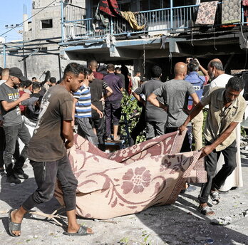 Palestinos usan una alfombra para trasladar a una de las víctimas del ataque a la escuela.