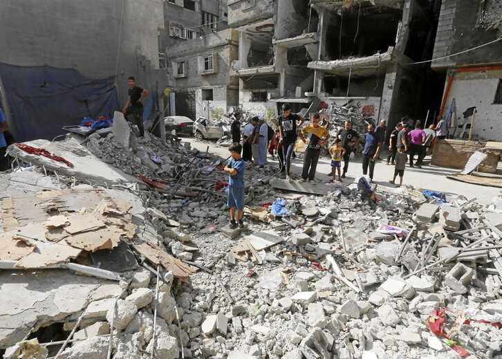 Palestinos entre los restos de una cada destruida en Nuseirat.