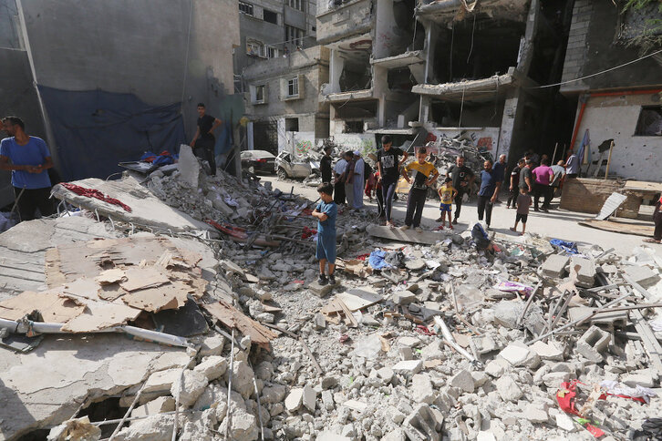 Palestinos entre los restos de una casa destruida en Nuseirat.