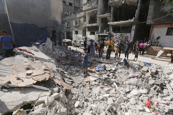 Palestinos entre los restos de una cada destruida en Nuseirat.