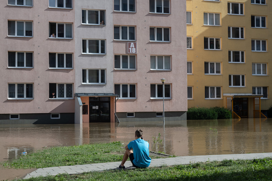 Un niño sentado frente a las casas inundadas por el río Opava.