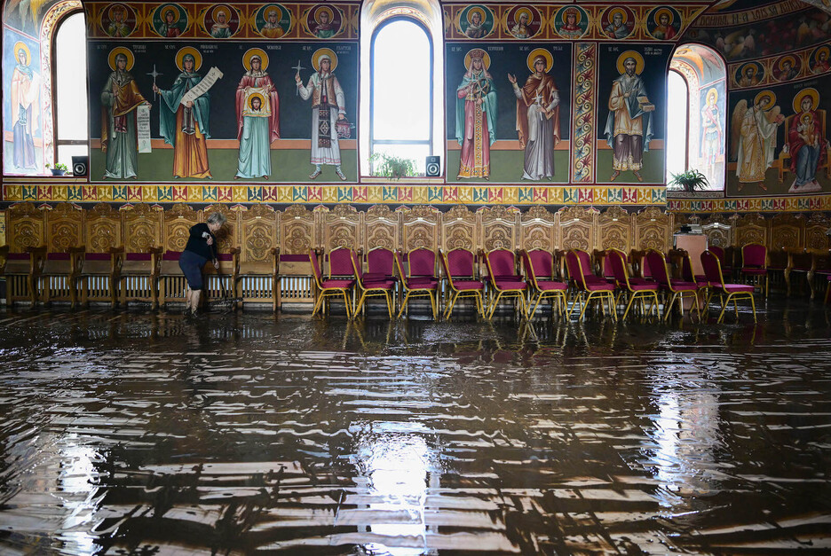 Una mujer limpia el suelo de una iglesia después de que el agua de la inundación se retirara del pueblo de Pechea, Rumanía.