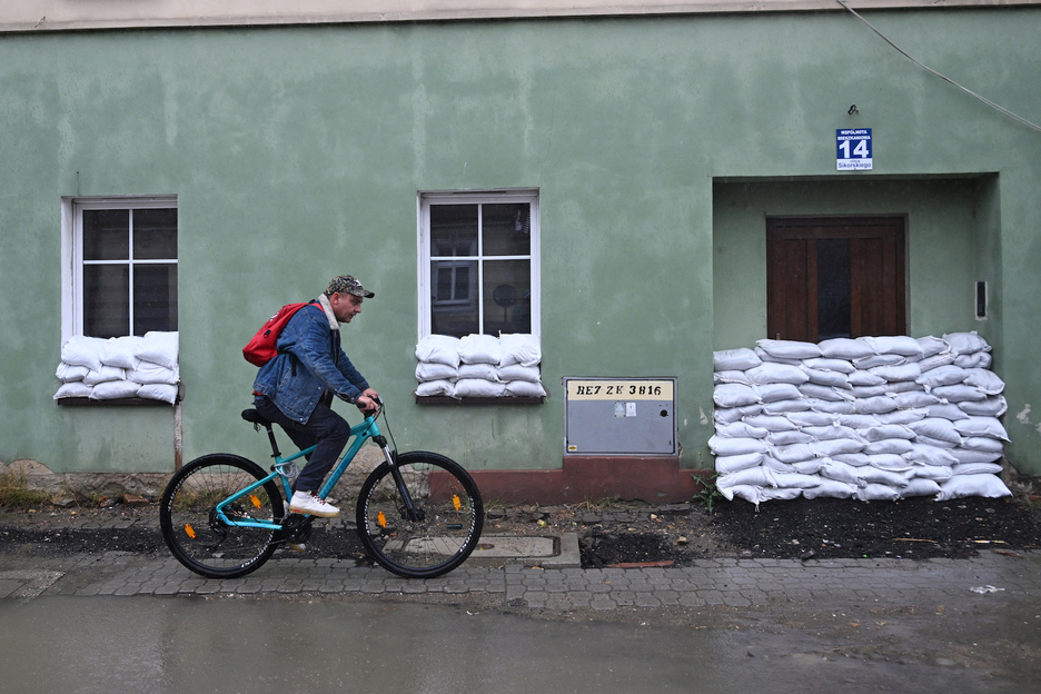 Un hombre pasa en bicicleta junto a una casa protegida contra las inundaciones con sacos de arena en Glucholazy.