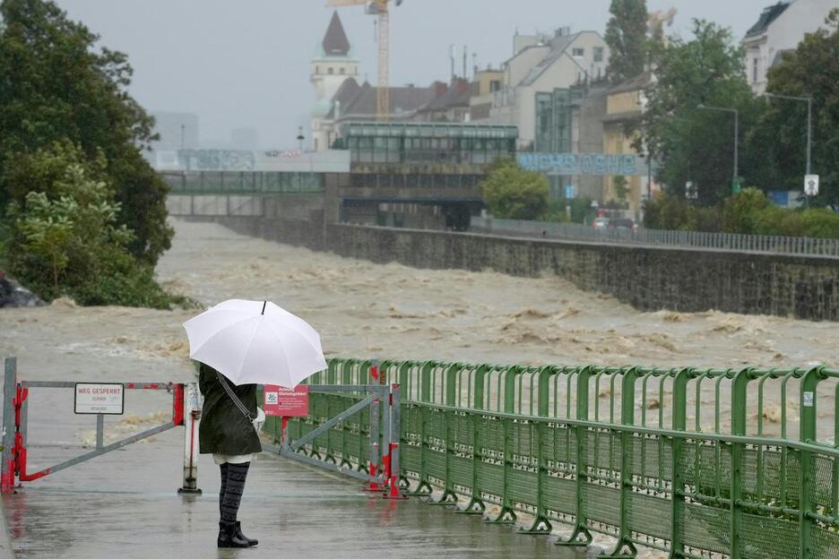 Un peatón observa el alto nivel del río Wien en Hutteldorf, Viena.