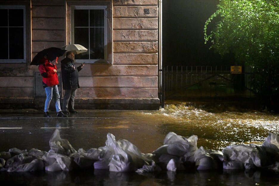  Vecinos de Glucholazy toman fotos con sus teléfonos móviles mientras el agua del río Biala llega al centro de la ciudad.