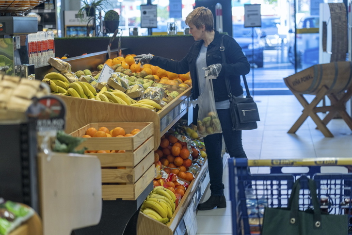 Una mujer en la sección de frutería de un supermercado.