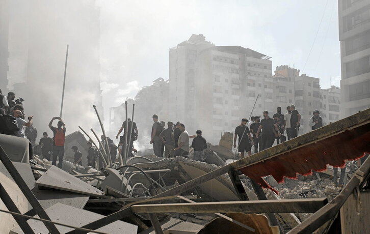 Libaneses observan un edificio totalmente destruido.