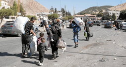 Personas desplazadas cruzan el paso fronterizo de Masnaa, desde Líbano hacia Siria.