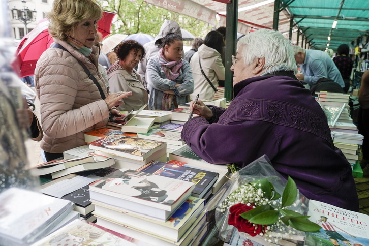 Toti Martínez de Lezea atiende a una lectora en la feria del libro que se celebró en abril en Bilbo.