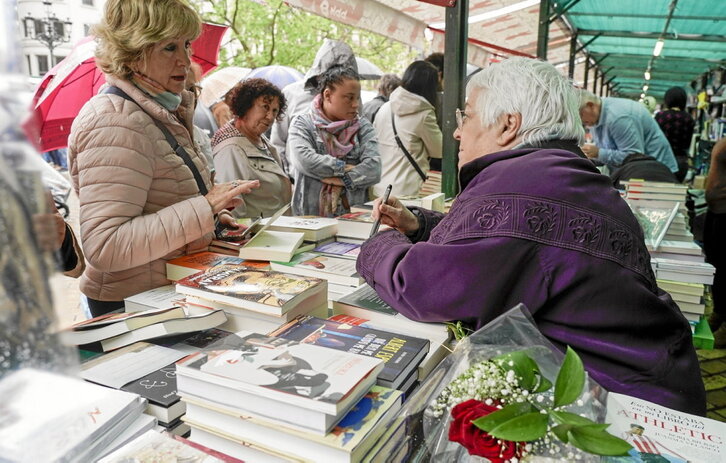 Toti Martínez de Lezea atiende a una lectora en la feria del libro que se celebró en abril en Bilbo.