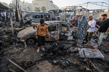 Palestinos, entre los restos calcinados del campamento atacado en el hospital Al Aqsa. 