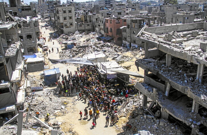 Palestinos esperan recibir comida entre las ruinas de la ciudad de Gaza.