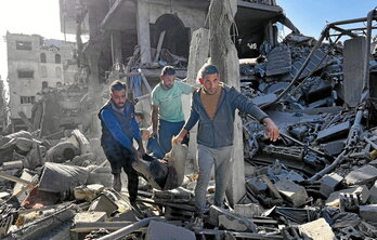 Varios hombres llevan en una manta uno de los cadáveres recuperados entre las ruinas en el edificio destruido en Beit Lahia.