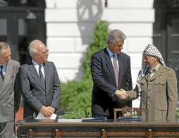 Isaac Rabin (izda.) contempla el saludo de Bill Clinton a Yasser Arafat durante la firma de los Acuerdos de Oslo en 1993.