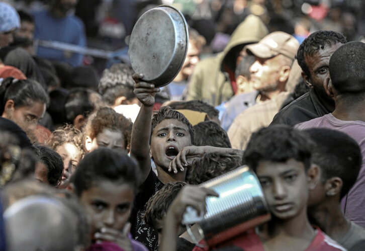 Niños palestinos esperan para recibir comida en Deir al Balah.