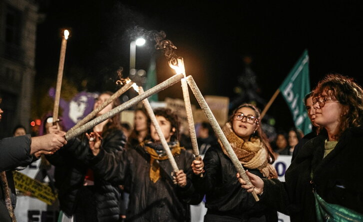 Unas manifestantes comparten fuego para prender sus antorchas en Baiona.