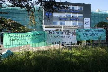 Fachada del Hospital Donostia, donde está contratada esta empresa, con varias pancartas sindicales en primer plano.