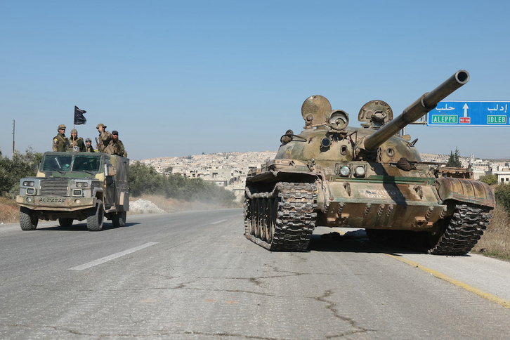   Yihadistas pasan junto a un tanque abandonado por el Ejército en la carretera que lleva de Alepo a Hama.