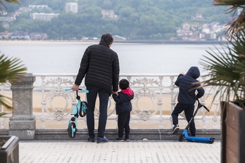 Un padre con dos niños paseando por Donostia.