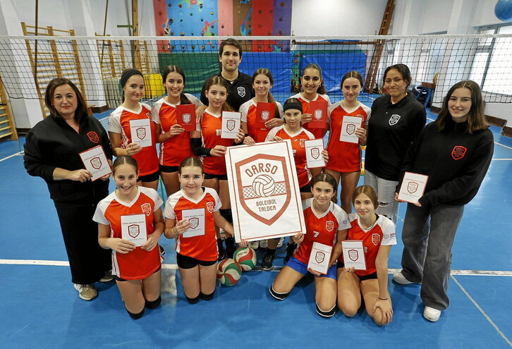 Oarso Boleibol Taldeko jokalariak, entrenamendu baten aurretik, argitaratu berri den hiztegitxoa erakusten.