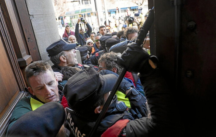 En el lado izquierdo, Máximo López, alcalde de Lazagurria, liderando la carga de los agricultores contra la puerta del Parlamento.