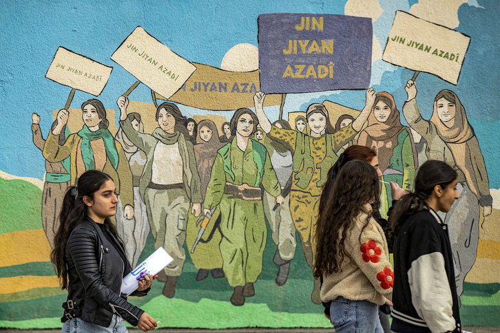 Una chica pasa junto a un mural en Qamishlo (Rojava), que recuerda las protestas de mujeres kurdas.