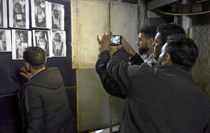 En la página anterior, familias en un hospital, buscando cuerpos de desaparecidos. Arriba, en busca de pistas en las fichas de la cárcel de Saidnaya.