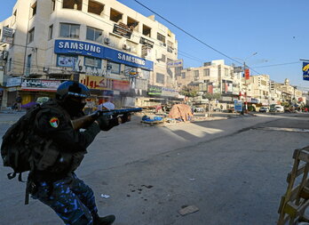 Un miembro de las fuerzas de la Autoridad Palestina dispara en una calle de Jenin.