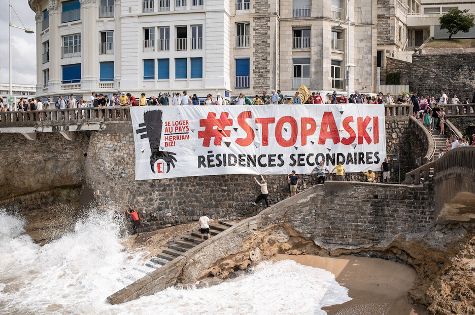 Le 18 août à Biarritz, La plateforme « Se loger au Pays - Herrian Bizi » déploie une banderole géante pour dénoncer la prolifération des résidences secondaires. 