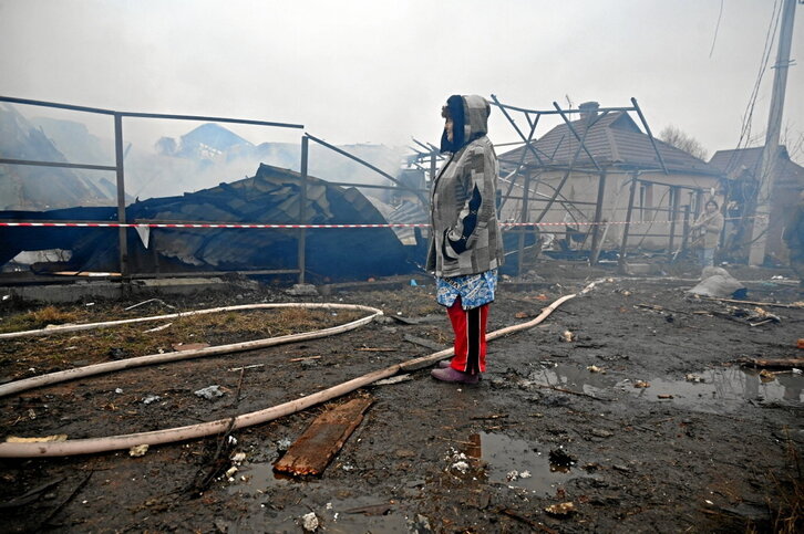 Una mujer observa una casa destruida por un dron en Jarkov.