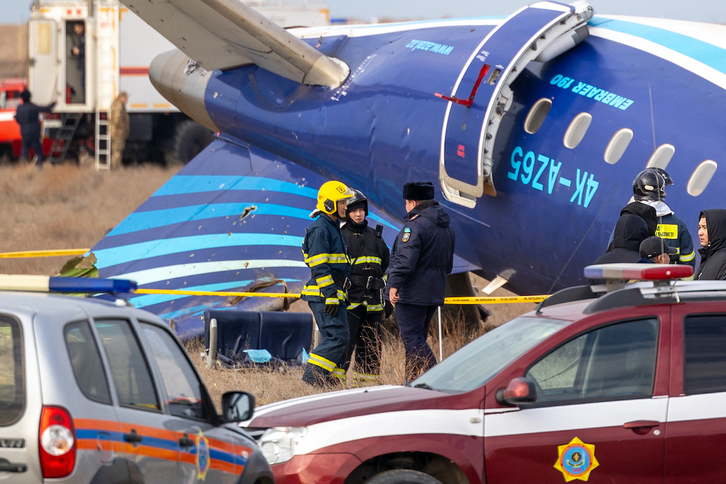 Restos del avión caído el miércoles, entre efectivos policiales y bomberos kazajos.