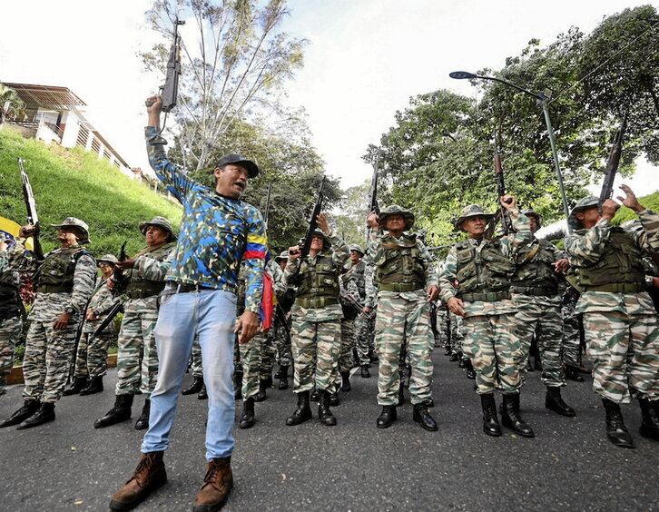 Miembros de la Milicia Bolivariana alzan sus rifles.