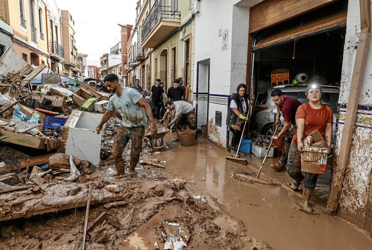 Un grupo de voluntarios y voluntarias intenta limpiar y desescombrar una calle de la localidad valenciana de Paiporta, completamente arrasada tras el paso de la dana de finales de octubre.