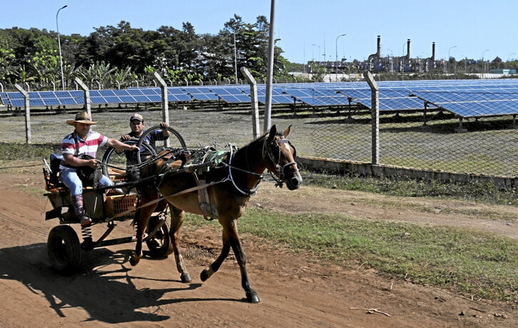 Un carruaje tirado por un caballo pasa junto a un parque fotovoltaico en Yaguaramas, en la provincia cubana de Cienfuegos.