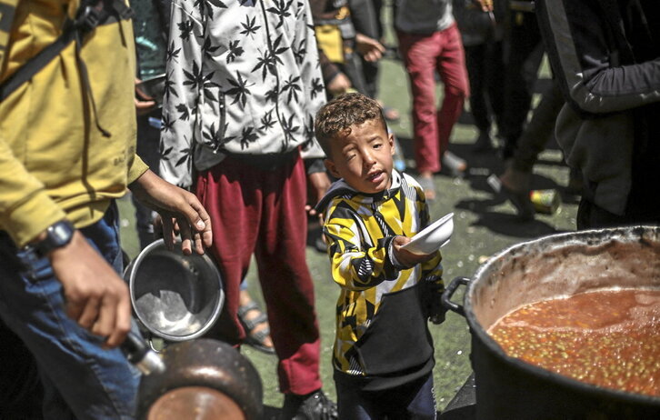 Un niño palestino espera recibir comida en uno de los comedores benéficos en el campamento de Nuseirat.