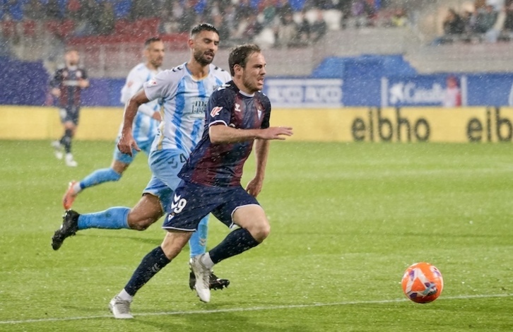 Bautista, autor del primer gol, corre bajo la intensa lluvia perseguido por Einar.